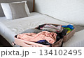 Traveler packing an open suitcase on the bed, organizing essentials for an upcoming journey 134102495