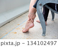 Young Asian woman massaging her ankle on balcony chair, calming wellness moment with fresh air 134102497