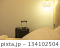 Travel-ready large suitcase placed by the bed in a neat room, showing journey and accommodation 134102504
