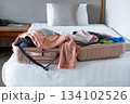 Open suitcase on hotel bed with travel items being prepared, capturing vacation planning moment 134102526