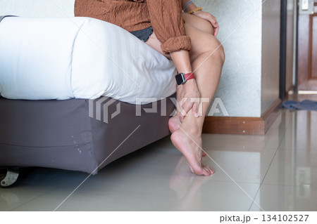 Young Asian woman massaging her ankle on the bed, soothing pain relief and peaceful relaxation Young Asian woman massaging her ankle on the bed, soothing pain relief and peaceful relaxation 134102527