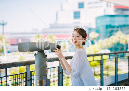 望遠鏡で観光地の景色を楽しむ若い女性 134103253