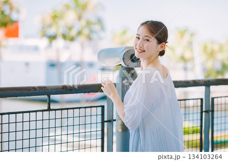 望遠鏡で観光地の景色を楽しむ若い女性 134103264