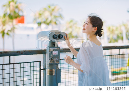 望遠鏡で観光地の景色を楽しむ若い女性 134103265