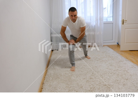 forward lunges exercise Strong Athletic Fit Man in T-shirt and Shorts is Doing Forward Lunge Exercises at Home in His Spacious and Bright Apartment with Minimalistic Interior. 134103779