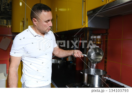Preparing sugar syrup for soaking cake crust. Professional chef pouring water. 134103793