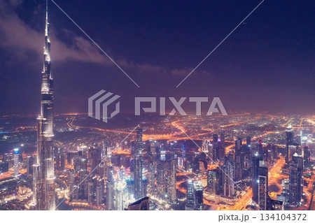 Stunning night aerial view of the Burj Khalifa and Downtown Dubai skyline, featuring illuminated skyscrapers and vibrant city lights in the UAE. 134104372