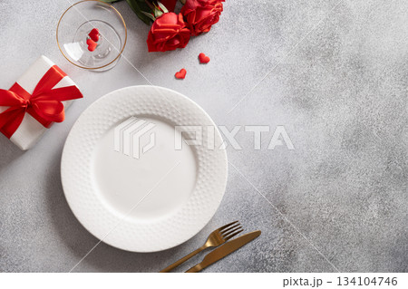 Festive table place setting with gift and red rose on gray background. View from above. Copy space. Romantic dinner for Valentine's day. 134104746