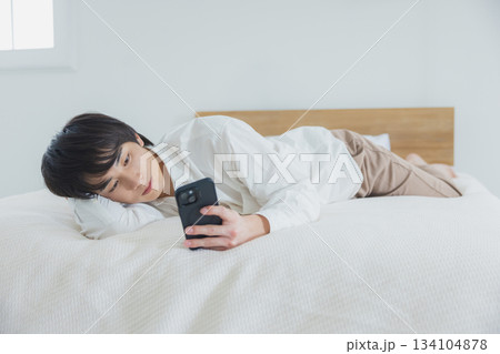 ベッドでスマホを見る男性 134104878