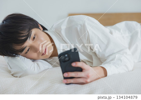 ベッドでスマホを見る男性 134104879