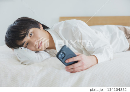 ベッドでスマホを見る男性 134104882