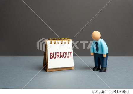 Emotional and physical exhaustion caused by prolonged stress and overwork. Concept of fatigue, depression, and work-life imbalance. Office worker or businessman stands near an easel with word burnout Emotional and physical exhaustion caused by prolonged stress and overwork. Concept of fatigue, depression, and work-life imbalance. Office worker or businessman stands near an easel with word burnout 134105061