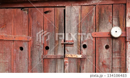 Barn plank doors with a deadbolt, distressed plank surface and rusting metal fasteners, barn texture background, closed doors with beautiful texture of the outbuilding close-up as a design banner 134106483