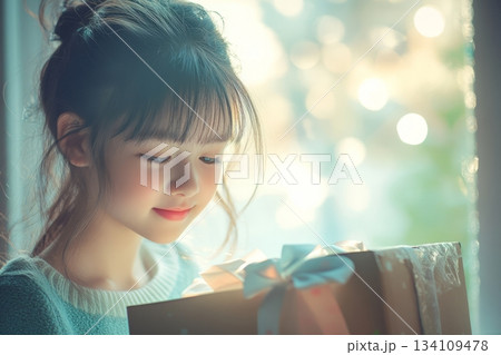 Little girl joyfully holding a colorful gift box with a big smile on her face 134109478