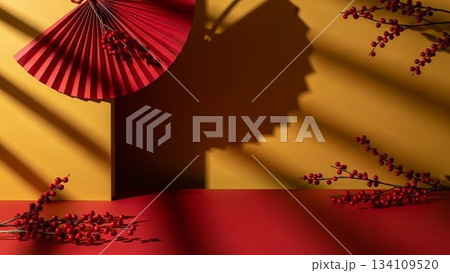 赤い扇子と南天の実を配した黄色と赤の背景に光と影のストライプがかかった和風デザイン 134109520