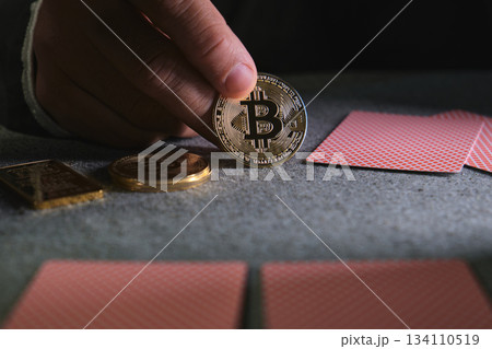 Hand holding bitcoin coin playing cards on casino table 134110519
