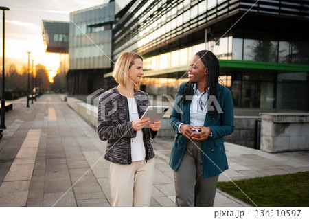 Diverse businesswomen walking and collaborating using digital tablet 134110597