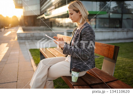 Businesswoman using digital tablet on bench enjoying sunset Businesswoman using digital tablet on bench enjoying sunset 134110620
