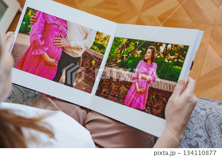 woman is holding and flipping through a photo book with a pregnancy photo shoot woman is holding and flipping through a photo book with a pregnancy photo shoot 134110877
