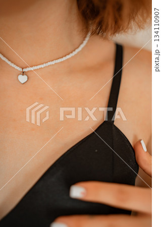 Close-up view of a delicate heart necklace on a woman's neckline 134110907