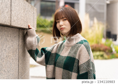 ビルの壁の前でポーズをとる女性 134110983