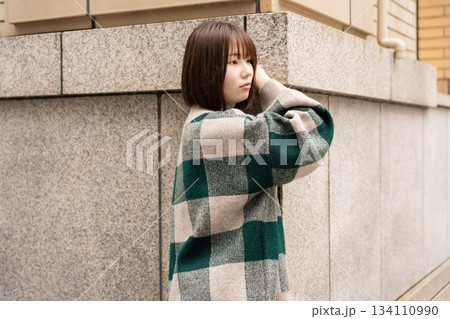 ビルの壁の前でポーズをとる女性 134110990