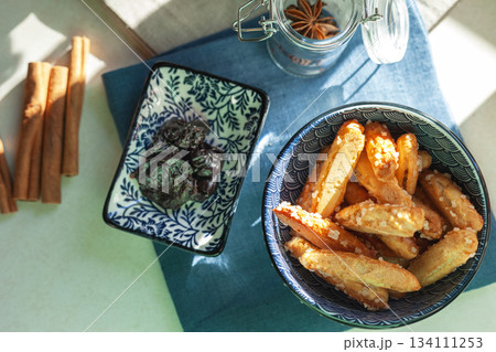 Choux pastry sticks in a ceramic bowl, next to them are cinnamon sticks and dried plums 134111253