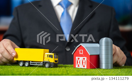 A businessman drives a truck to a farm. Establishing logistics in retail and agricultural production. Supply chain integration and rural delivery. Agribusiness, retail logistics and food distribution. 134111279