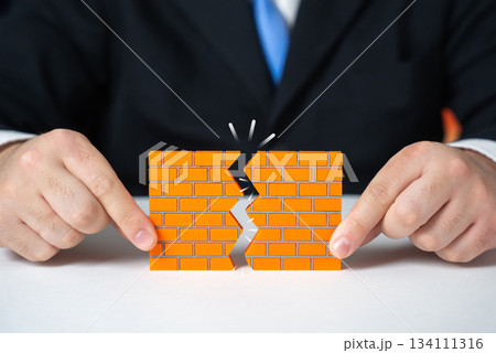 A businessman makes a hole in a brick wall. Overcoming obstacles and barriers. Strategic breakthrough and determination. Leadership inspiration, innovation and overcoming corporate challenges. 134111316