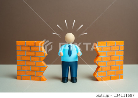 An office worker breaks down a wall. Overcoming barriers and obstacles to achieve progress. Workplace innovation and determination. Leadership content, productivity improvements and motivation 134111687