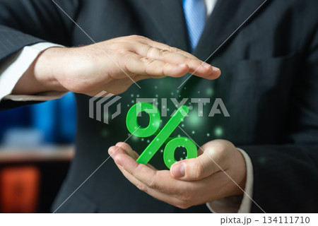 A businessman keeps his green interest in his hands. Attractive interest rates on deposits and favorable loan terms. Financial benefits and banking opportunities. Investment, personal finance and loan A businessman keeps his green interest in his hands. Attractive interest rates on deposits and favorable loan terms. Financial benefits and banking opportunities. Investment, personal finance and loan 134111710