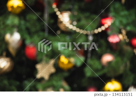 Blurred Christmas tree with red and golden balls and lights garland. Abstract pattern. Defocused background. Xmas holiday spirit. Blurred Christmas tree with red and golden balls and lights garland. Abstract pattern. Defocused background. Xmas holiday spirit. 134113151