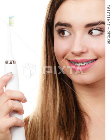 Woman brushing teeth with braces using brush Woman brushing teeth with braces using brush 134113191