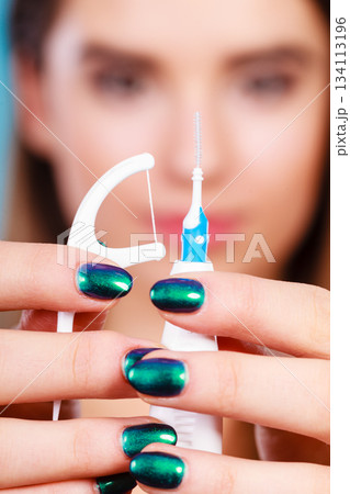 Woman holding small toothbrush and dental floss 134113196