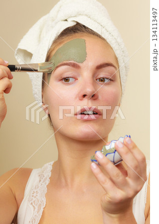 Woman applying with brush clay mud mask to her face Woman applying with brush clay mud mask to her face 134113497