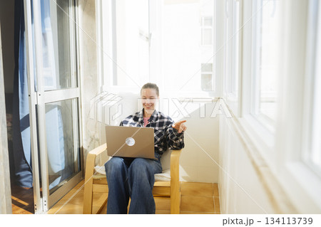 Woman in jeans relaxing on balcony while working remotely Woman in jeans relaxing on balcony while working remotely 134113739
