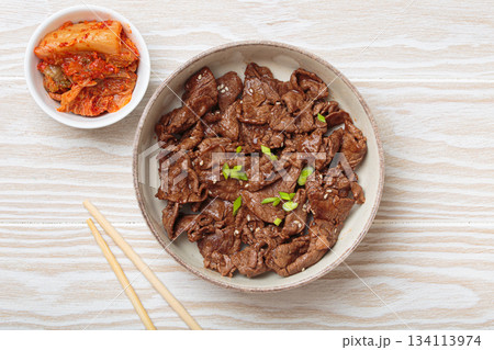 Bulgogi, grilled marinated beef Korean dish with kimchi and sesame seeds top view on white wooden background 134113974