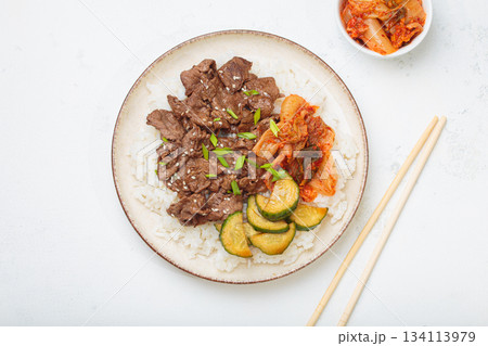 Korean beef bulgogi bowl dish with rice, roasted meat, kimchi and marinated cucumber on white background top view with chopsticks Korean beef bulgogi bowl dish with rice, roasted meat, kimchi and marinated cucumber on white background top view with chopsticks 134113979