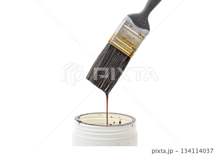 A black bristle paint brush is placed over a can of white lacquer with lacquer dripping from the brush back into the can A black bristle paint brush is placed over a can of white lacquer with lacquer dripping from the brush back into the can 134114037