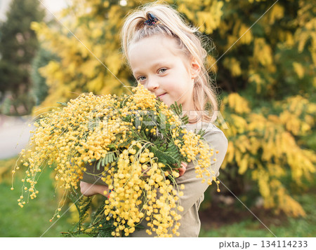 Child Holding Mimosa Bouquet in a Garden Setting Child Holding Mimosa Bouquet in a Garden Setting 134114233
