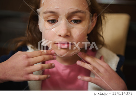Face portrait of beautiful child girl applying moisturizing face mask Face portrait of beautiful child girl applying moisturizing face mask 134114375