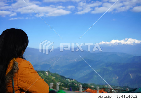 Woman Admires Majestic Kanchenjunga Mountains with Blue Sky 134114612