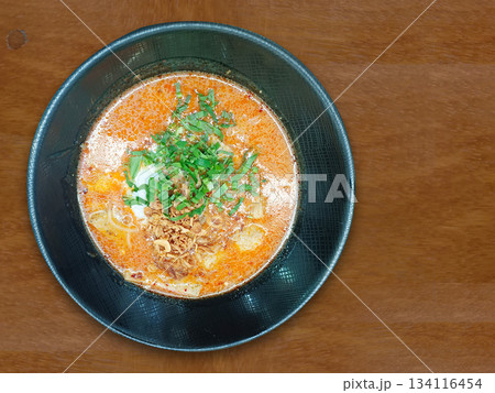 top view Kuay Jap Yuan Tom Yum with vegetables, pork sausage, and pork in a black ceramic bowl on a wooden floor background, food, object, delicious, yummy, copy space top view Kuay Jap Yuan Tom Yum with vegetables, pork sausage, and pork in a black ceramic bowl on a wooden floor background, food, object, delicious, yummy, copy space 134116454