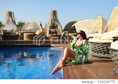 Tourist relaxing by the pool at a luxury resort enjoying summer vacation 134116775