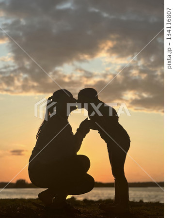 Mother kissing daughter at sunset by the lake Mother kissing daughter at sunset by the lake 134116807