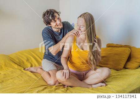 Man giving a gentle shoulder massage to a woman while sitting together on the bed, creating a warm and intimate moment at home. Relaxation, wellness, care and relationship concept, showing comfort Man giving a gentle shoulder massage to a woman while sitting together on the bed, creating a warm and intimate moment at home. Relaxation, wellness, care and relationship concept, showing comfort 134117341