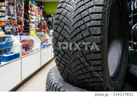 Studded tire with detailed tread pattern displayed in auto shop, showing traction and durability Studded tire with detailed tread pattern displayed in auto shop, showing traction and durability 134117652