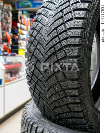 Studded winter tire tread displayed in auto shop showing detailed pattern and traction design Studded winter tire tread displayed in auto shop showing detailed pattern and traction design 134117653