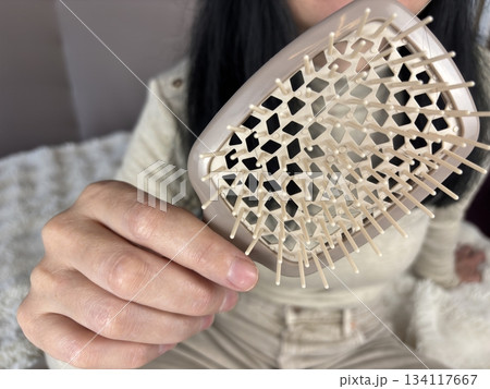 Adult brunette woman holding a hairbrush after brushing, concept of hair care and hair loss concern 134117667