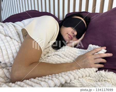 Brunette adult woman sleeping wearing a sleep mask, peaceful night rest, healthy sleep habits, deep relaxation in cozy bedroom, insomnia prevention and bedtime routine Brunette adult woman sleeping wearing a sleep mask, peaceful night rest, healthy sleep habits, deep relaxation in cozy bedroom, insomnia prevention and bedtime routine 134117699